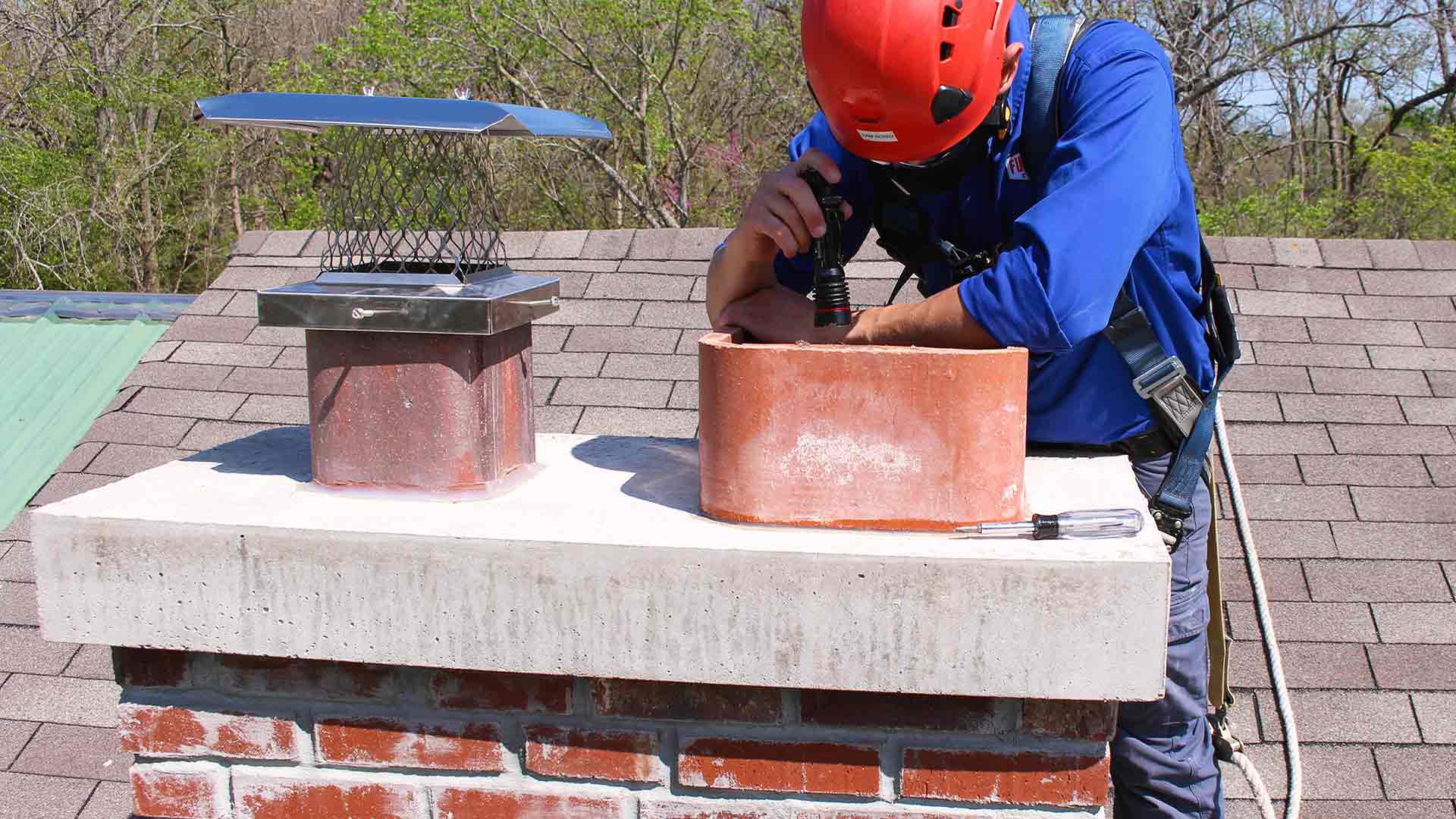 Certified technician inspecting chimney flue from rooftop for fireplace safety compliance