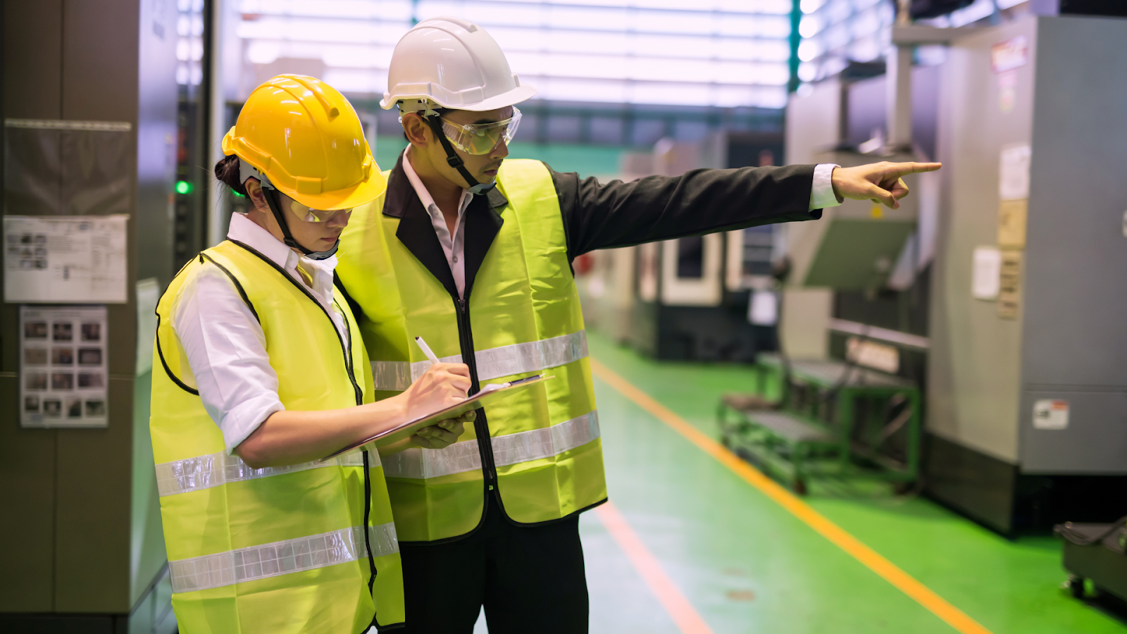 Two inspectors in safety vests reviewing notes during a commercial building inspection