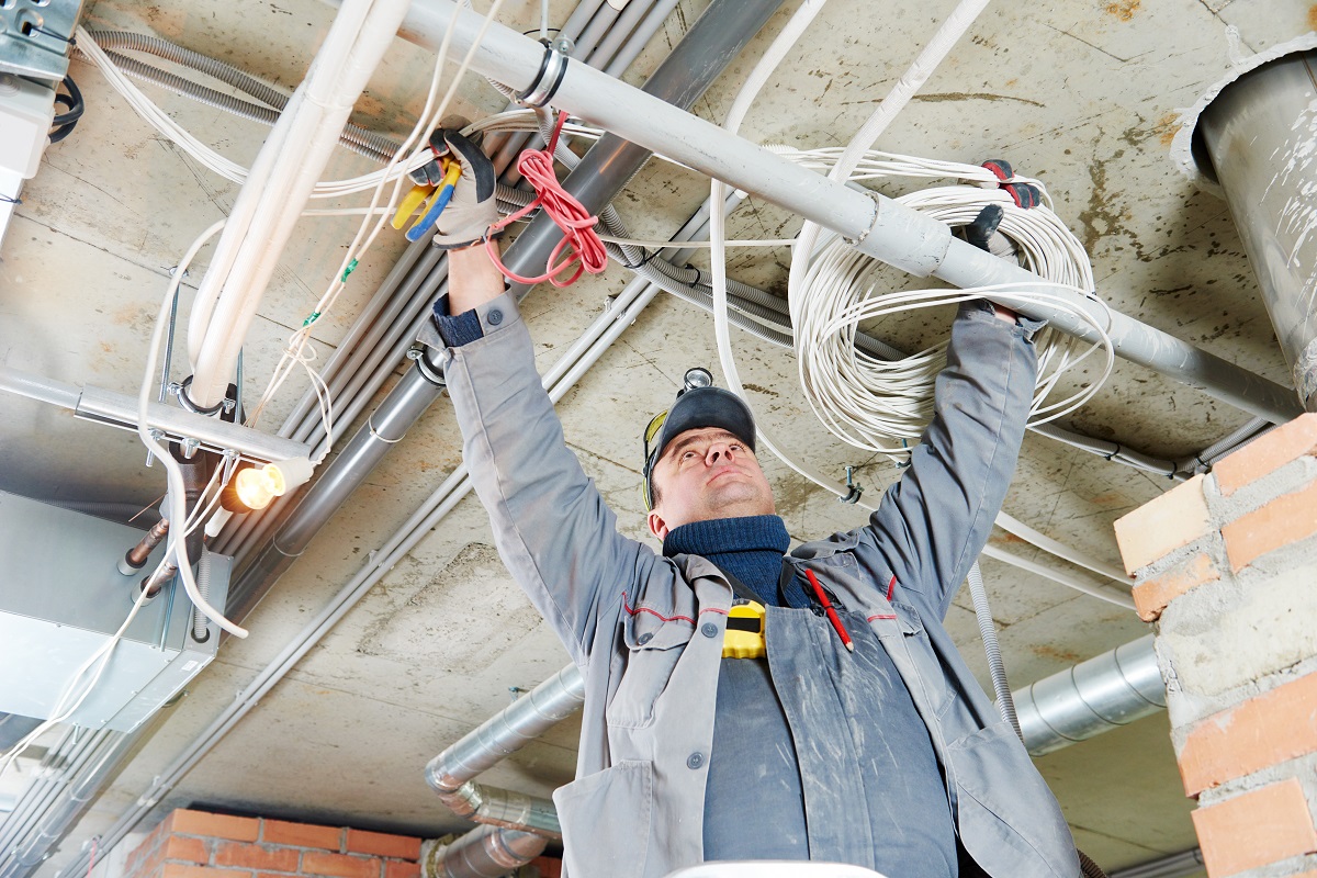 Inspector checking ceiling wiring and plumbing system during a home inspection